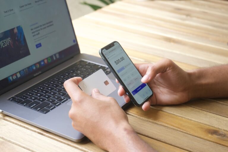 Usuario de banca digital utiliza un smartphone y una tarjeta junto a un portátil